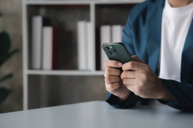Business man looking at financial information from a mobile phone, he is checking company financial documents, he is an executive of a startup company. Concept of financial management.