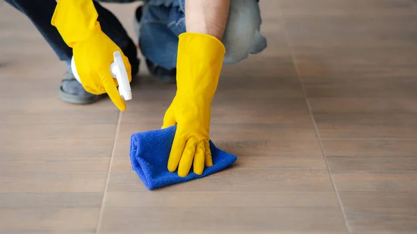 Person cleaning the room, cleaning staff is using cloth and spraying disinfectant to wipe the floor in the company office room. Cleaning staff. Maintaining cleanliness in the organization.