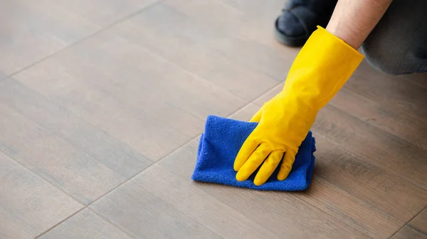 Person cleaning the room, cleaning staff is using cloth and spraying disinfectant to wipe the floor in the company office room. Cleaning staff. Maintaining cleanliness in the organization.