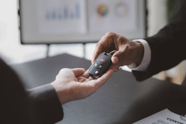 Bir araba kiralama şirketi çalışanı, kiracıyla kira sözleşmesini detaylar ve kiralama şartları hakkında konuştuktan sonra imzalaması gerektiğine işaret etti. Araba kiralama kavramı.