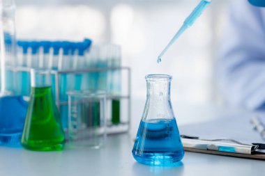 Laboratuvar asistanı, tıp bilimcisi, kimya araştırmacısı kan örneğinde cam bir tüp tutuyor, kimyasal bir deney yapıyor ve hastanın kan örneğini inceliyor. Tıp ve araştırma konsepti.