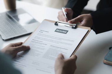 A person attends a job interview with a manager to join a company, he holds a resume and interview with information introducing himself and his ability to work. Job application concept.