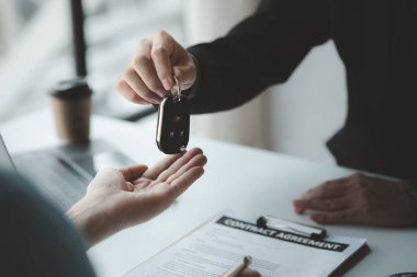 A car salesman is explaining the purchase details and details in the car purchase contract before signing acceptance of the terms, the car sales contract through an agent. Car trading concept.