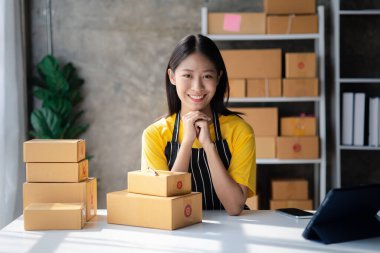 Bir çevrimiçi mağazanın sahibi, paketlenmiş ürünlerin siparişlerini web sitesinden sipariş edildiği gibi müşterilere teslimata hazırlamak için kontrol etmektedir. Çevrimiçi satış ve online alışveriş kavramları.