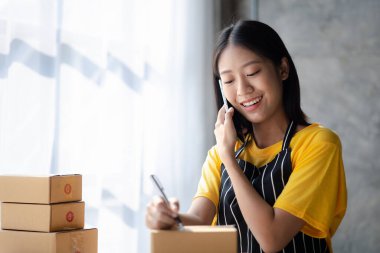 Online store salesperson is writing a customer's shipping address on parcel box before sending it to private carrier for delivery to customer. The idea of opening an online store and packing products.