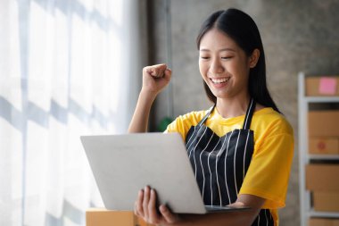 Bir çevrimiçi mağazanın sahibi, paketlenmiş ürünlerin siparişlerini web sitesinden sipariş edildiği gibi müşterilere teslimata hazırlamak için kontrol etmektedir. Çevrimiçi satış ve online alışveriş kavramları.