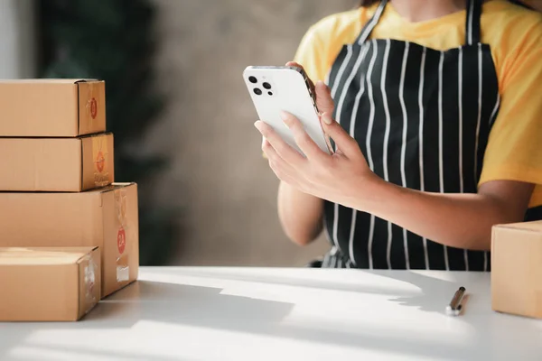 Online store salesperson is writing a customer\'s shipping address on parcel box before sending it to private carrier for delivery to customer. The idea of opening an online store and packing products.