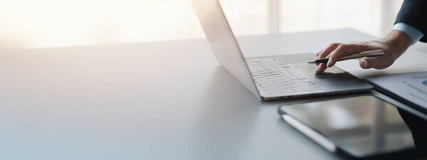 Person typing on laptop keyboard, businessman working on laptop, he is typing messages to colleagues and making financial information sheet to sum up the meeting.