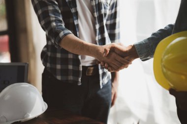 Team engineers and architects shake hands with the condo project owners after the meeting to present room plans and details of the condo building structure. Concept of building design and construction