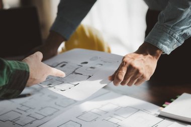 The home design architects are reviewing the house plan draft, the project commissioned by the client, and the custom design before delivery. Interior design and decoration ideas.