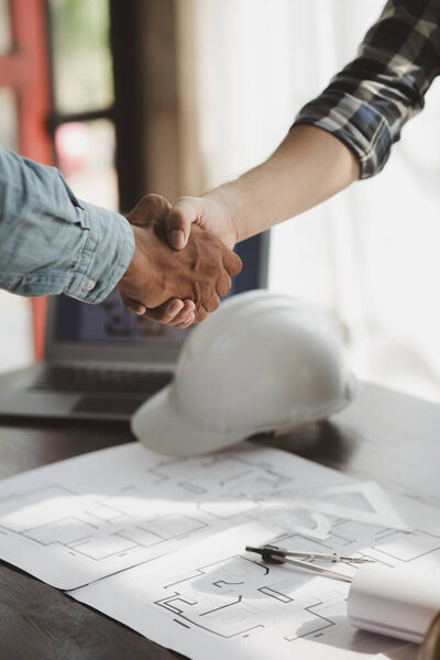 Team engineers and architects shake hands with the condo project owners after the meeting to present room plans and details of the condo building structure. Concept of building design and construction