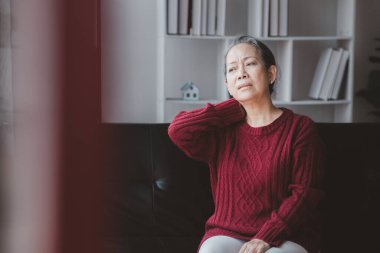 Oturma odasında oturan yaşlı kadın vücut ağrıları, yaşlanma hastalıkları, yaşlı insanların vücut ağrıları, organ dejenerasyonu..