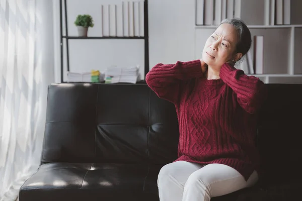 stock image Senior woman sitting in the living room at home and showing body aches, aging sickness, body aches of elderly people, organ degeneration.