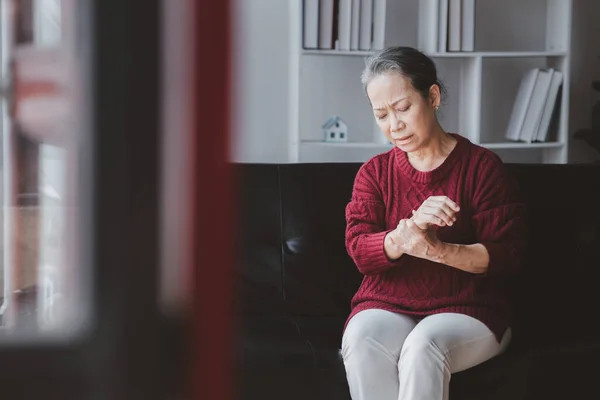 stock image Senior woman sitting in the living room at home and showing body aches, aging sickness, body aches of elderly people, organ degeneration.