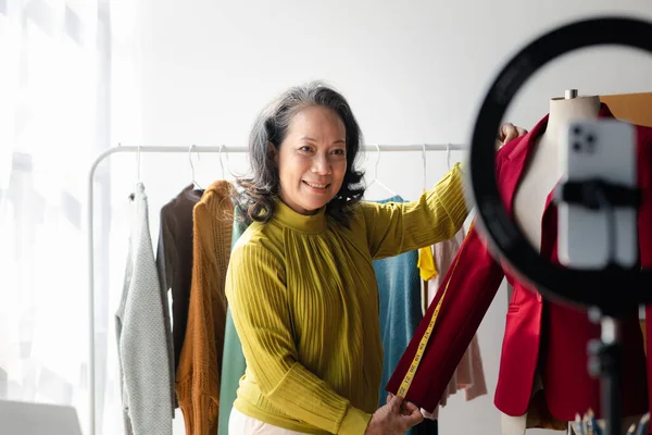 Elderly women are designers who make clothes, she is the owner of a female fashion clothing store and designs clothes and cutting sets, selling products through online and live websites.