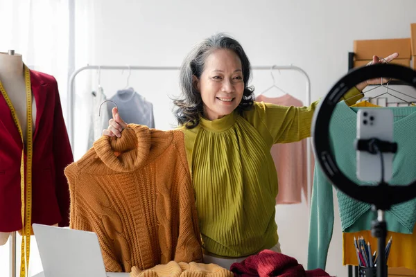 Elderly women are designers who make clothes, she is the owner of a female fashion clothing store and designs clothes and cutting sets, selling products through online and live websites.