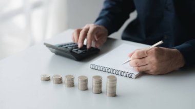 Bir işadamı gelirinin ve harcamalarının kaydını tutuyor, daha hızlı büyümesi için aylık tasarruflarını kullanarak para kazanmayı planlıyor. Yatırım için para biriktirme kavramı.