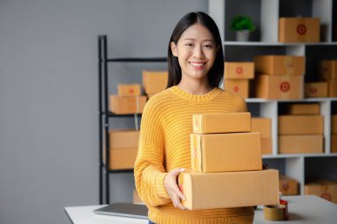 A beautiful business owner opens an online store, she is checking orders from customers, sending goods through a courier company, concept of a woman opening an online business.