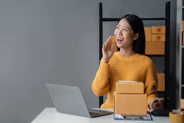 A beautiful business owner opens an online store, she is checking orders from customers, sending goods through a courier company, concept of a woman opening an online business.