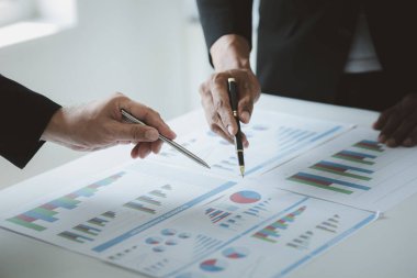 Two businessmen are brainstorming together and reviewing the company financial documents that the finance department has summarized, they are business partners. Business administration concept.