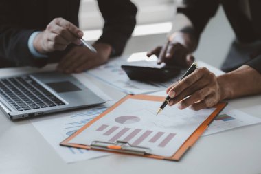 Two businessmen are brainstorming together and reviewing the company financial documents that the finance department has summarized, they are business partners. Business administration concept.