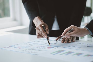 Two businessmen are brainstorming together and reviewing the company financial documents that the finance department has summarized, they are business partners. Business administration concept.