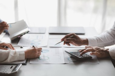 Company meeting room has businessmen and finance managers meeting together on finance topics, they are looking at information on documents and discussing together. Concept company financial management