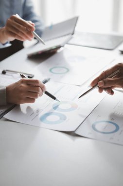 Company meeting room has businessmen and finance managers meeting together on finance topics, they are looking at information on documents and discussing together. Concept company financial management