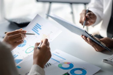 Company meeting room has businessmen and finance managers meeting together on finance topics, they are looking at information on documents and discussing together. Concept company financial management