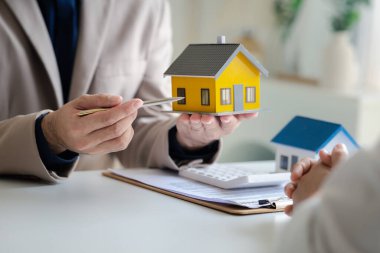 Real estate agents explain models of housing estates in projects to elaborate to clients, explaining and presenting information about homes and purchasing loans. Real estate trading concept.