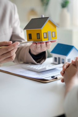 Real estate agents explain models of housing estates in projects to elaborate to clients, explaining and presenting information about homes and purchasing loans. Real estate trading concept.