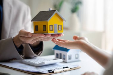 Real estate agents explain models of housing estates in projects to elaborate to clients, explaining and presenting information about homes and purchasing loans. Real estate trading concept.