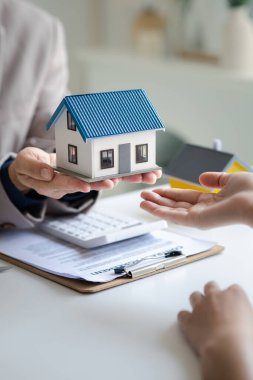 Real estate agents explain models of housing estates in projects to elaborate to clients, explaining and presenting information about homes and purchasing loans. Real estate trading concept.