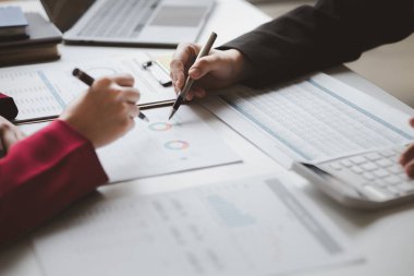 Two businessmen are brainstorming together and reviewing the company financial documents that the finance department has summarized, they are business partners. Business administration concept.