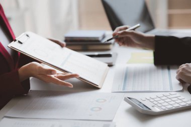 Two businessmen are brainstorming together and reviewing the company financial documents that the finance department has summarized, they are business partners. Business administration concept.