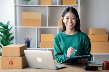 The owner of an online store is checking orders for packaged products in order to prepare them for delivery to customers as ordered through the website. Online selling and online shopping concepts.