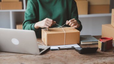 Müşteri kutusuna paket bağlayan bir kadın, çevrimiçi bir mağazası var, özel bir nakliye şirketi aracılığıyla paketleyip gönderiyor. Çevrimiçi satış ve online alışveriş kavramları.
