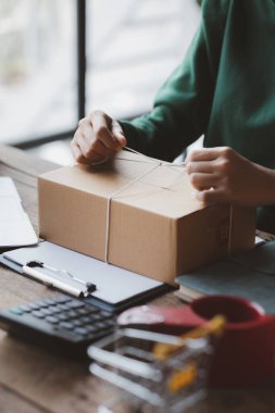 Müşteri kutusuna paket bağlayan bir kadın, çevrimiçi bir mağazası var, özel bir nakliye şirketi aracılığıyla paketleyip gönderiyor. Çevrimiçi satış ve online alışveriş kavramları.