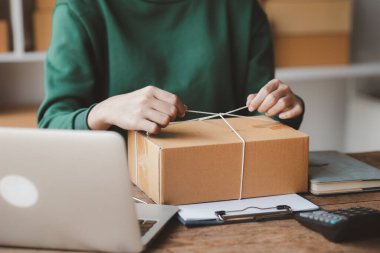 Müşteri kutusuna paket bağlayan bir kadın, çevrimiçi bir mağazası var, özel bir nakliye şirketi aracılığıyla paketleyip gönderiyor. Çevrimiçi satış ve online alışveriş kavramları.