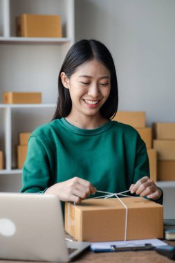 Müşteri kutusuna paket bağlayan bir kadın, çevrimiçi bir mağazası var, özel bir nakliye şirketi aracılığıyla paketleyip gönderiyor. Çevrimiçi satış ve online alışveriş kavramları.