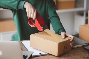 Bir kişi siparişlere göre paket kutuları topluyor, çevrimiçi bir mağazası var, özel bir nakliye şirketi aracılığıyla paketleyip gönderiyor. Çevrimiçi satış ve online alışveriş kavramları.