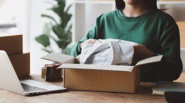 Bir kişi siparişlere göre paket kutuları topluyor, çevrimiçi bir mağazası var, özel bir nakliye şirketi aracılığıyla paketleyip gönderiyor. Çevrimiçi satış ve online alışveriş kavramları.