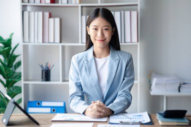 A businesswoman is checking company financial documents and using a tablet to talk to the chief financial officer through a messaging program. Concept of company financial management.