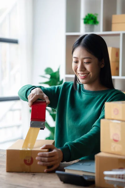 stock image A person is packing parcel boxes according to orders, she owns an online store, she packs and ships through a private transport company. Online selling and online shopping concepts.