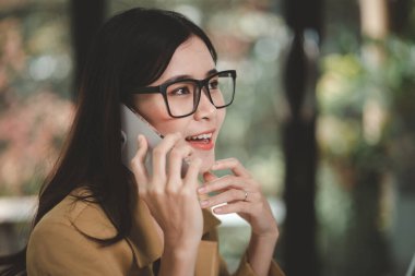 Asian woman talking on the phone, she is a salesperson in a startup company, she is calling customers to sell products and promotions. Concept of selling products through telephone channels.