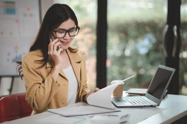 Telefonda konuşan Asyalı bir kadın, bir girişim şirketinde satış elemanı, ürün ve promosyon satmak için müşterileri arıyor. Telefon kanalları aracılığıyla ürün satma kavramı.