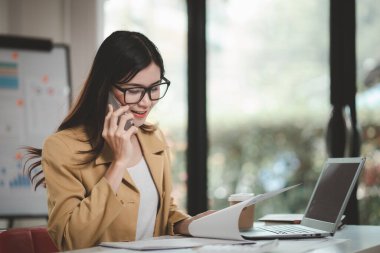 Telefonda konuşan Asyalı bir kadın, bir girişim şirketinde satış elemanı, ürün ve promosyon satmak için müşterileri arıyor. Telefon kanalları aracılığıyla ürün satma kavramı.