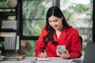 Cep telefonundan mali bilgilere bakan genç bir iş kadını, şirketin mali belgelerini kontrol ediyor, yeni kurulan bir şirketin kadın yöneticisidir. Mali yönetim kavramı.