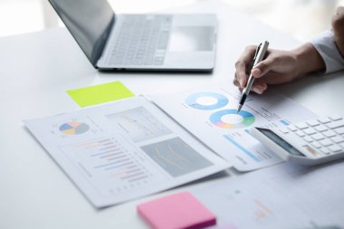 A female financier is reviewing company financial documents, monthly financial statement summary from the finance department. The concept of managing the company's finances for accuracy and growth.