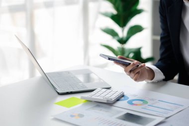 young businesswoman looking at financial information from a mobile phone, she is checking company financial documents, she is a female executive of a startup company. Concept of financial management.